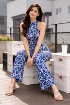 Woman in a blue floral jumpsuit sitting on white crates on a rooftop.