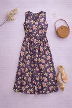 Floral dress with a round woven bag and sandals on a light purple background